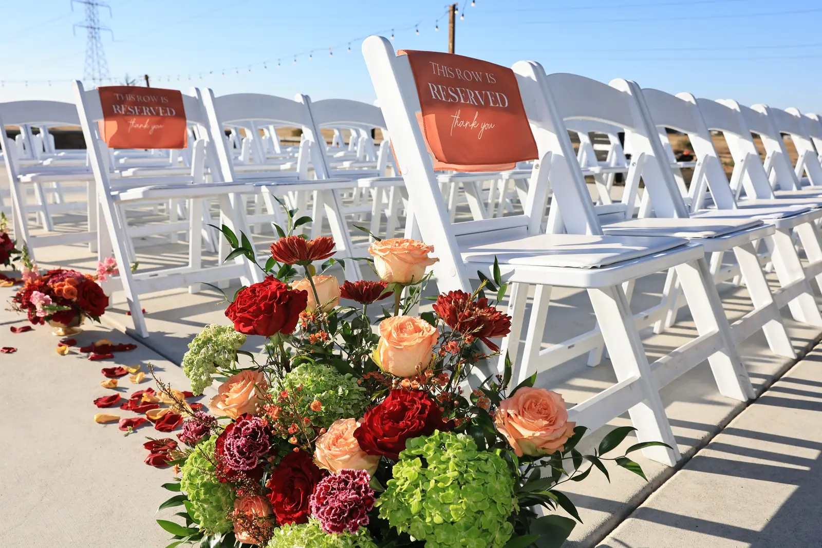 Aisle florals of red roses and green hydrangea beside reserved seating
