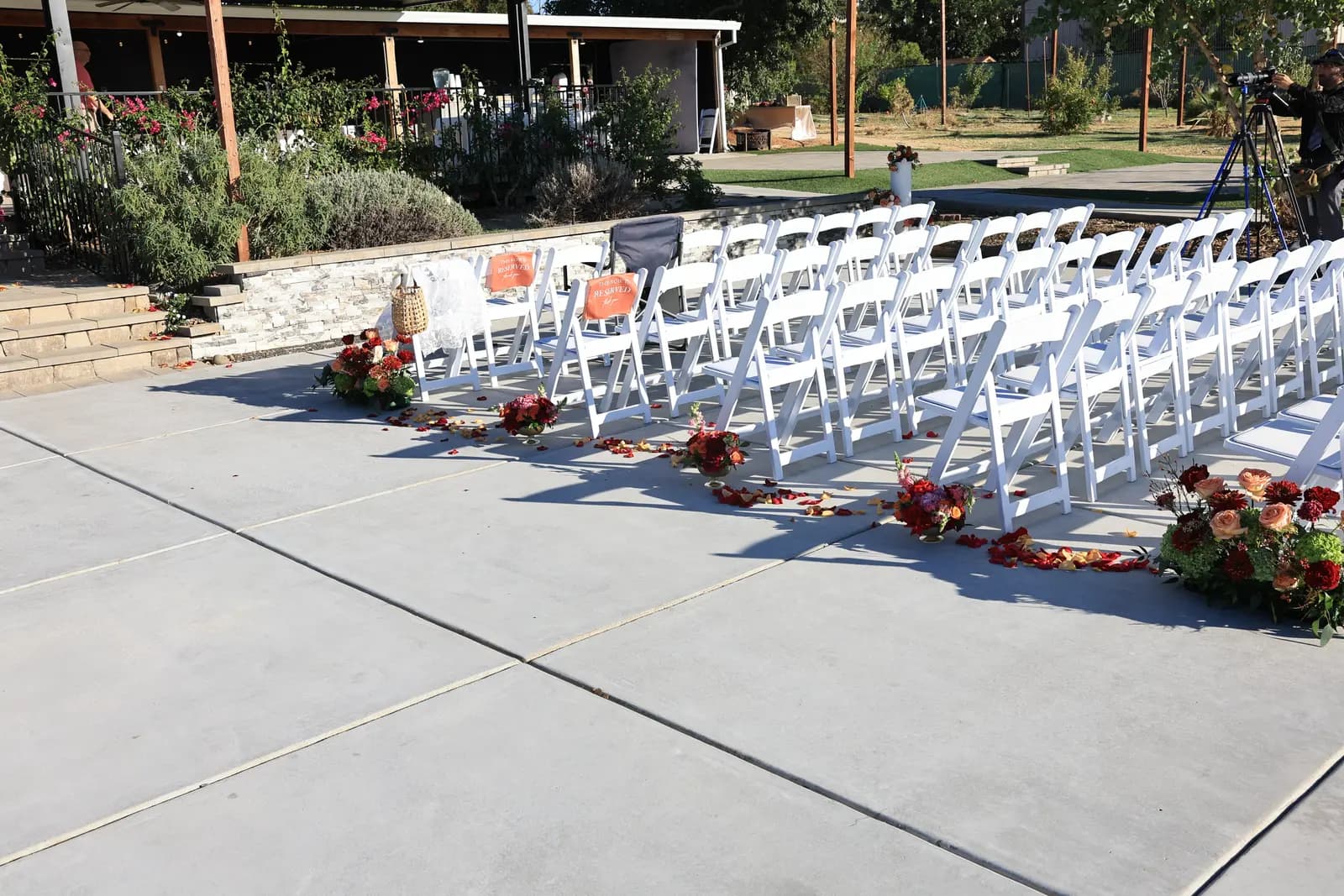 Outdoor ceremony aisle lined with white chairs and MAYDE rose arrangements