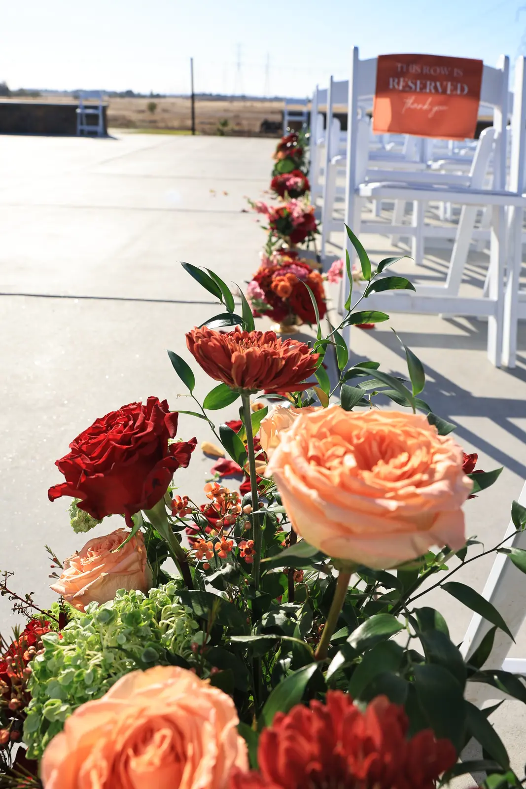 Close view of peach and red garden roses at the end of a ceremony row