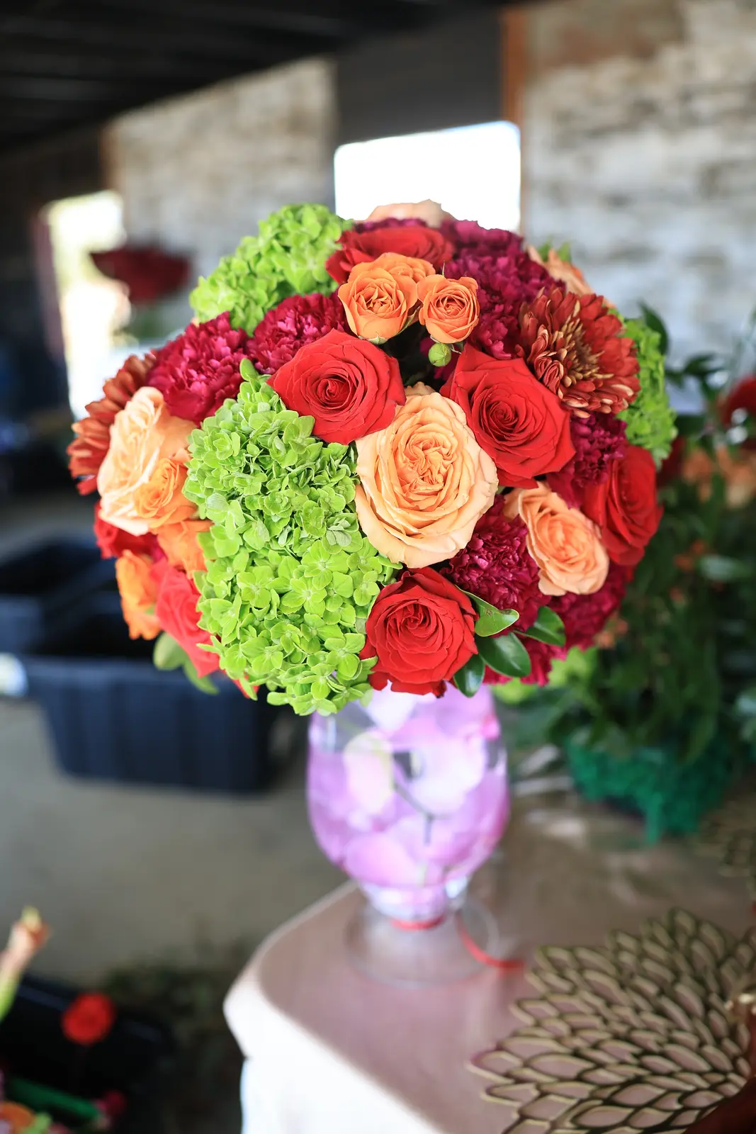 Tall centerpiece of red and coral roses with green hydrangea