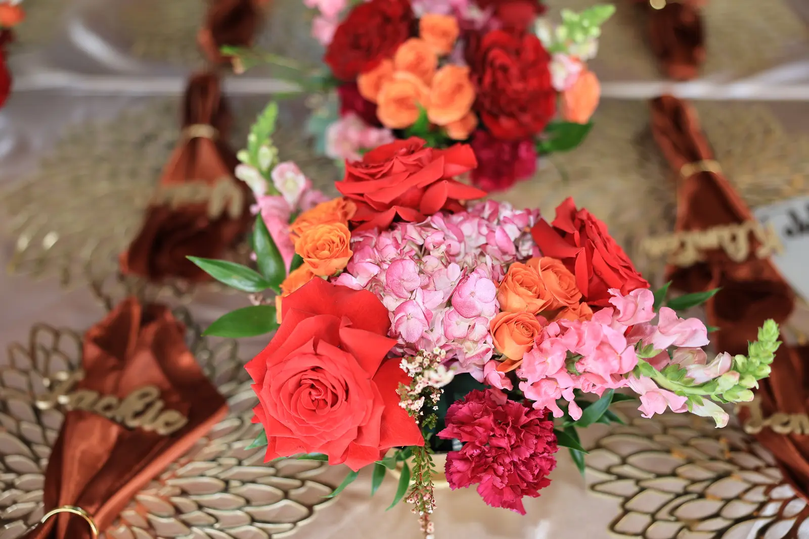 Roses and snapdragons on a gold charger at the reception table